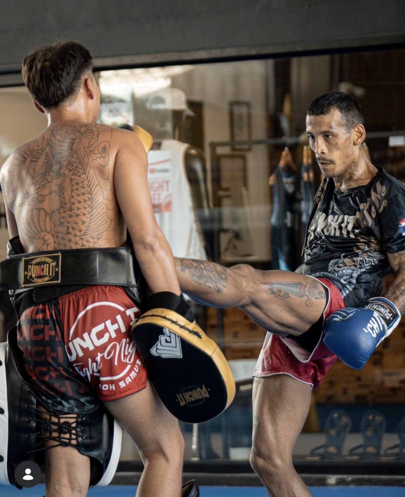 Carlitos Machado holds pads for a kick in a Thai gym